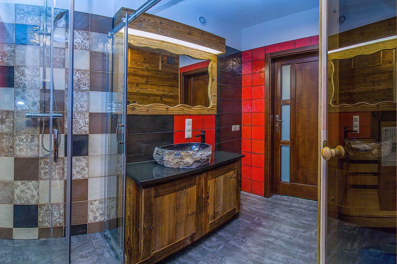 Drewniana szafka z kamienną umywalką i duże lustro w rzeźbionej ramie w łazience apartamentu