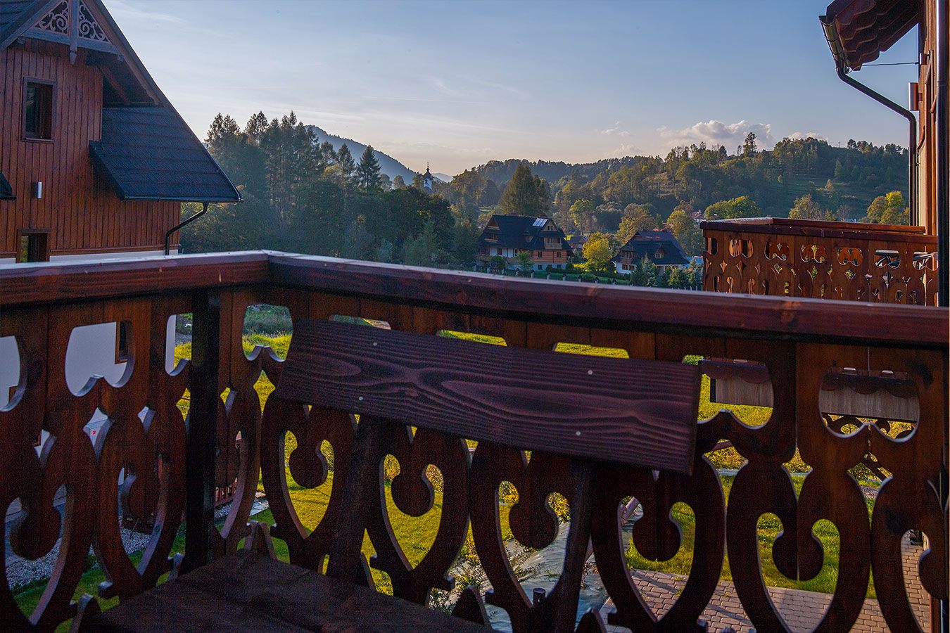 Autentyczny widok z rzeźbionego drewnianego balkonu na malowniczą panoramę gór i okoliczną architekturę Jaworek