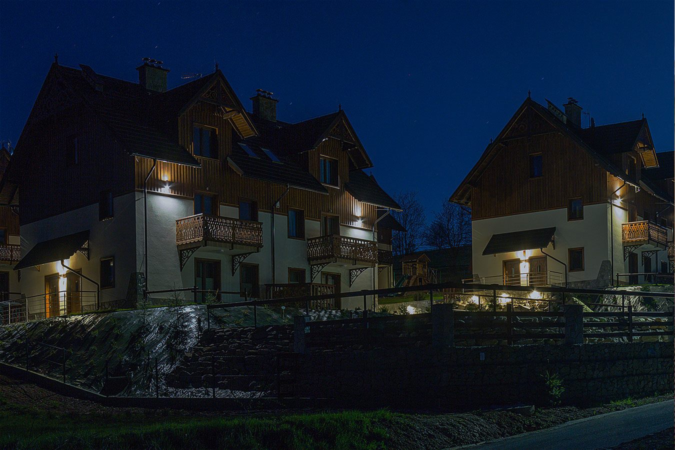 Nocny widok na elegancko oświetlone z zewnątrz budynki apartamentów w Jaworkach, podkreślający górski klimat
