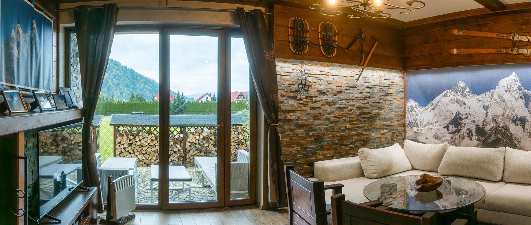 Strefa wypoczynkowa w Apartamencie na Szczycie ze ścianą wykończoną naturalnym kamieniem, dużą kanapą i widokiem na zewnątrz