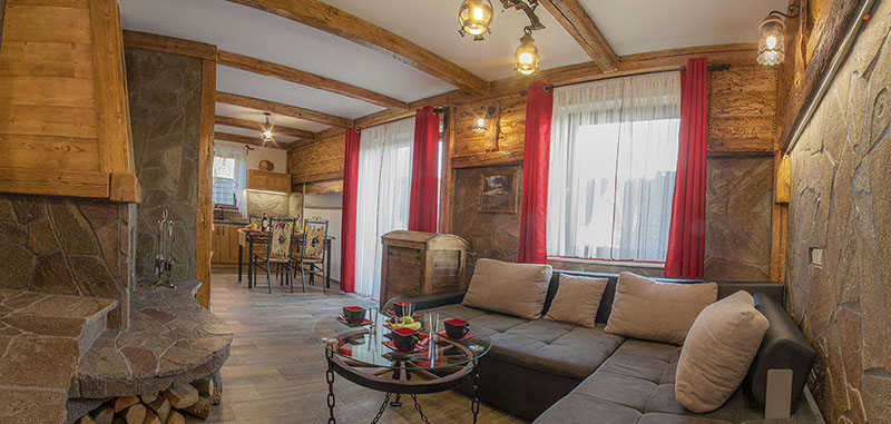 Salon w apartamencie z kominkiem w stylu góralskim. Wyjście z salonu na balkon z widokiem na góry. Apartament w Jaworkach. 